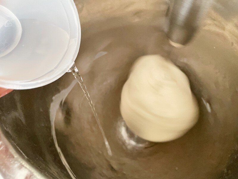 Pour the bassinage into developed dough